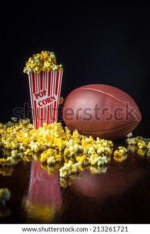 A close up shot of a classic box of red and white striped popcorn box with a fooball isolated against a black background.
