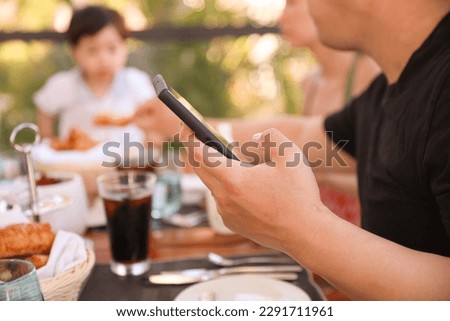 people holding phones at a dining table symbolizes the prevalence of technology in our modern lives, but also the potential distraction and lack of presence in social situations ストックフォト © 