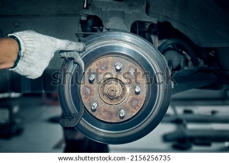 Deep grooves in old rusty disc brake rotors of the vehicle. Removal and replacement of rotors and pads. Brake Rotors Resurfacing. Braking System Repairs in garage. 商業照片 © 