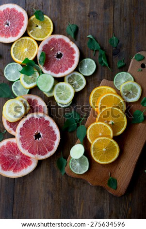 sliced citrus mix lemon grapefruit lime and orange in geometrical shapes on dark wood rustic background soft focus overhead-angle shot