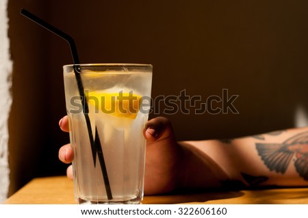healthy organic detox homemade traditional lemonade, cool girl with tattoos holding the glass cool shadows natural light background