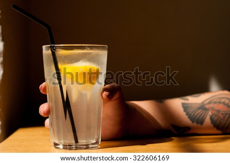 healthy organic detox homemade traditional lemonade, cool girl with tattoos holding the glass cool shadows natural light background