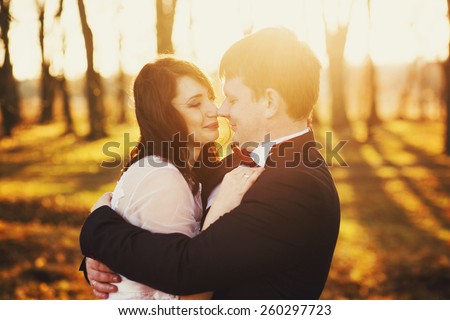 happy bride kissing on the background of sunset and forest in autumn