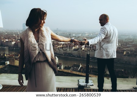 wonderful rich bride and groom holding hands on the terrace on the background of blue sky Lyon city