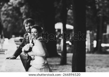 gentle beautiful bride and groom holding hands smiling looking at camera near the ancient fence balcony  Roma Italy black and white