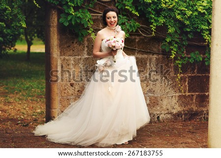 wonderful stylish rich happy bride with bouquet of peonies  at a wedding ceremony in green garden  Rome