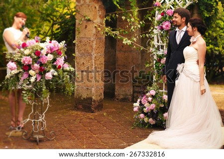 rich stylish happy bride and groom smiling holding  near a white wedding arch decorated with flowers peonies Rome Italy