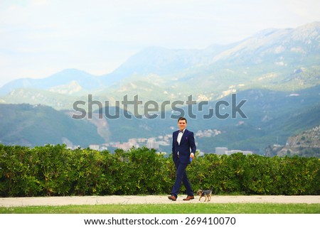 beautiful young rich groom walking on the beach with Yorkshire Terrier Montenegro