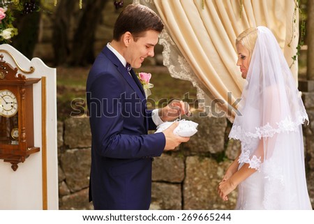wonderful stylish rich happy bride and groom put rings at a wedding ceremony in  garden near arch with flowers Montenegro