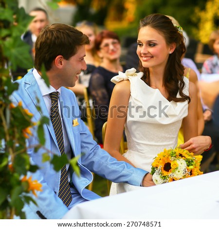 rich stylish groom and bride  holding hand near the arch of sunflowers