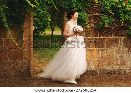 wonderful stylish rich happy bride with bouquet of peonies  at a wedding ceremony in green garden  Rome