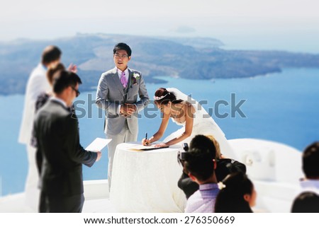 stylish rich asian bride and groom  put sign wedding tradition on the island of Santorini, Greece sunshine