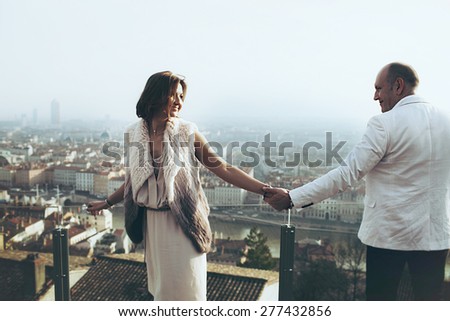 wonderful rich bride and groom  look at each other holding hands on the terrace on the background of blue sky Lyon city