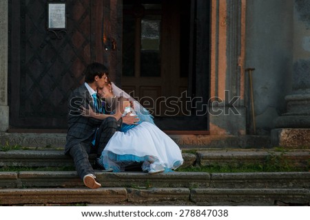cute couple is sitting on the stears, hugging and kissing on the background  columns