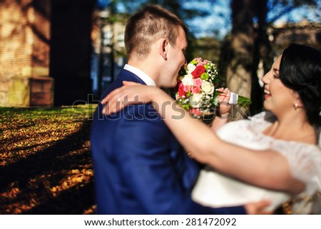 bride and groom walking fun near trees and church