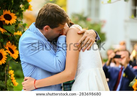 rich stylish groom and bride  kissing near the arch of sunflowers wedding ceremony