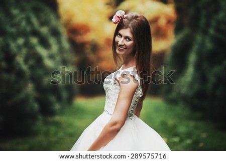 elegant stylish groom with his happy gorgeous brunette bride on the background of trees in the park