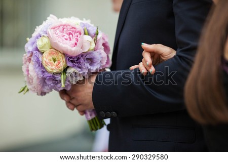 lovely charming cute stylish bouquet of purple pink and beige  peonies is holding fiance