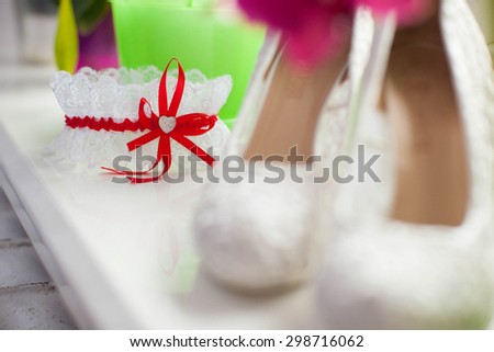 stylish wedding garter with red ribbon and small heart in the center, beautiful  high heels