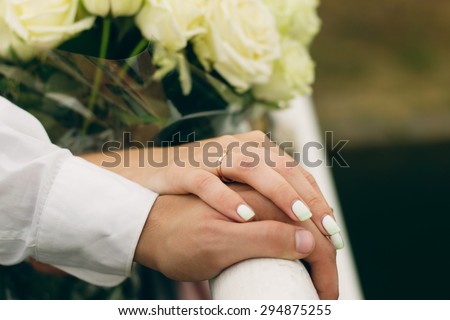 male and female hands together on the bridge railing
