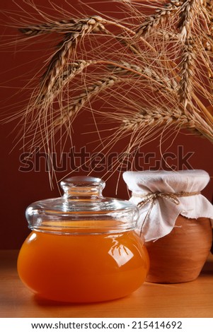 Honey in a glass jug and ripe ears