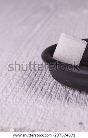Square piece of refined sugar on a black saucer