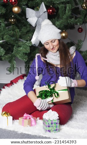 Young happy beautiful woman near new year tree with present
