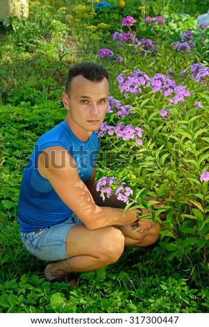 A young man about Bush Phlox on the plot in the summer on a Sunny day close up