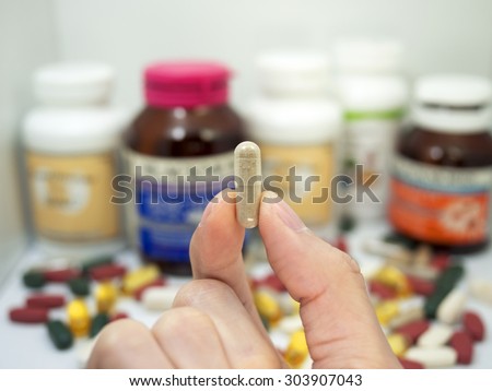 taking a vitamin tablet,pepper tablet,Pills or vitamin in Medicine bottles with pill box,Vitamin, drug,multivitamin, herbal supplement capsules, Colorful,pills and tablets, background