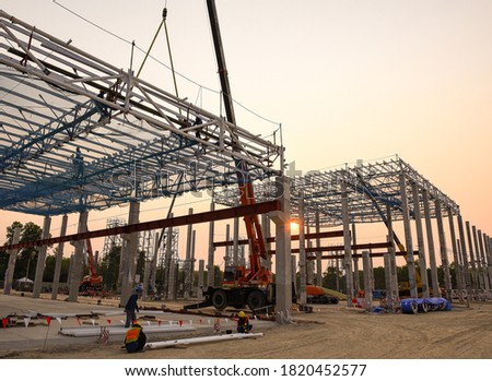 Construction workers are working at height above roof to instrallation accessory steel structure roof truss at construction site factory project during sunset time Сток-фото © 