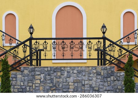 Stairs of colonial style building decorate with stone, metal bar with yellow building
