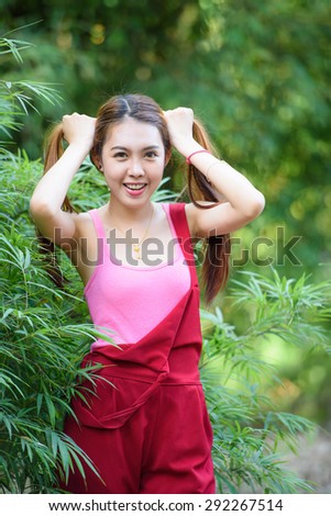 Cosplay style, portrait of a lovely girl with 2 pony tails hairstyle in red long leg suit behind green bamboo leaves background
