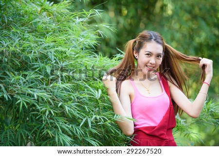 Maiden lovely girl like dressed cosplay style with two pony tails hairstyle in red long leg suit and green bamboo leaves background
