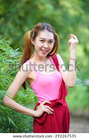 Maiden lovely girl like dressed cosplay style with two pony tails hairstyle in red long leg suit and green bamboo leaves background
