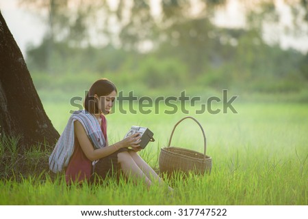 Peasant girl sat listening to the radio music transistors in rice fields happily at countryside Thailand
