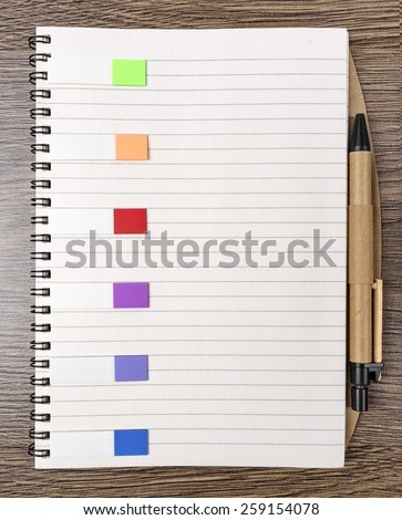 Colored stickers around notebook on old wooden table