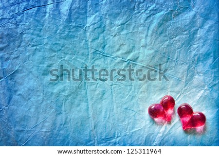 Two shining hearts over blue wrapping paper background