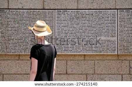 ROSSOSCHKA, RUSSIA - MAY 10, 2013: A young woman man looks for a relative's name on a German War Memorial in the Russian village of Rossoschka near the former city of Stalingrad.