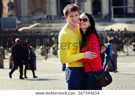 a couple of tourists smiling and enbracing on the central square of the Vatican