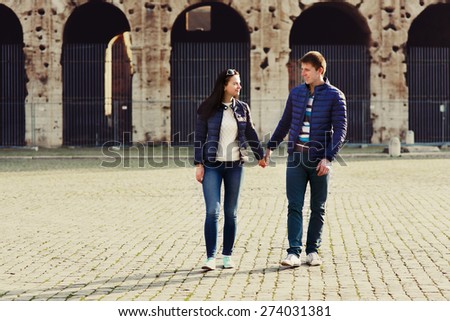 two people holding hands and walk near coliseum in Rome and carriage