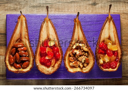 dessert of baked pears with honey, nuts and candied fruit. Dessert of pears lying on a purple board