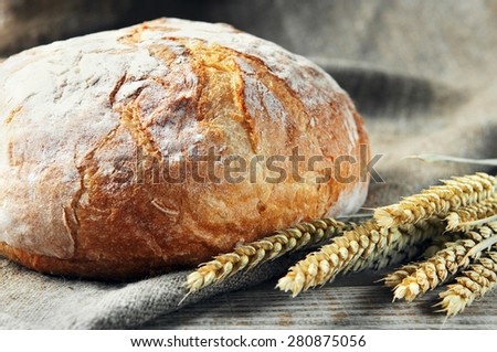 freshly baked, fresh, homemade bread with spikelets of wheat lying on a wooden table. rustic style. close-up
