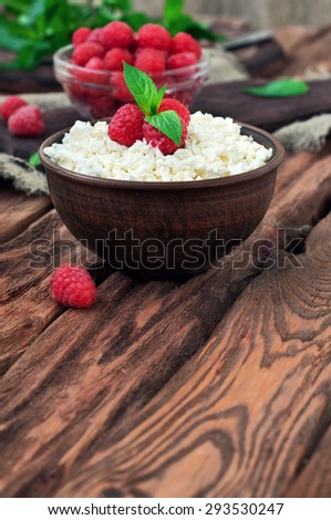 cottage cheese and fresh raspberries in a bowl on a wooden table, copy space. rustic style. A eye level