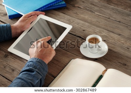 Men hand clicks on the screen blank tablet on wooden table. concept man working from home using tablet computer. Free space for text. Closeup. Top view