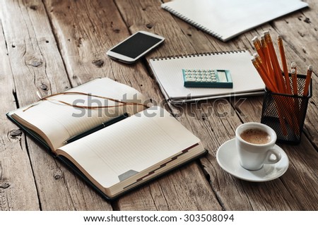 blank notebook on wooden table with a cup of black coffee and pencils. Closeup. Top view. Copy space. Free space for text