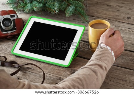 on the wooden table closeup white tablet computer, coffee cup, vintage camera and a sprig of spruce. Copy space. Free space for text