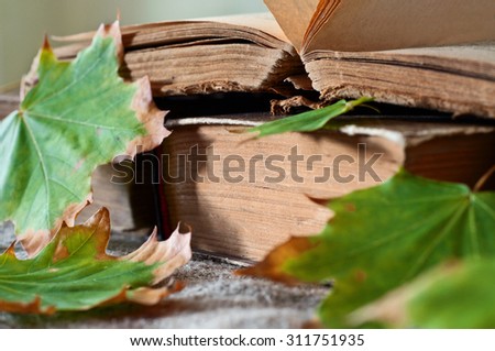 stack of vintage books in autumn maple leaves close up. Copy space. Free space for text