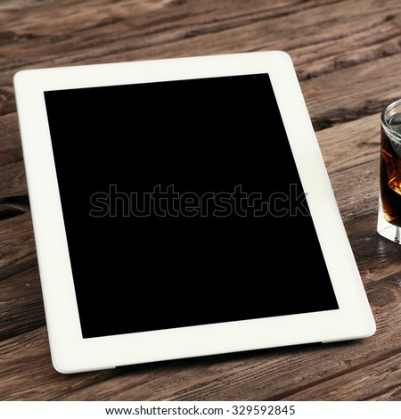 White tablet computer with a blank screen on the wooden table with a glass of cola with ice. Top view. Copy space. Free space for text. square frame
