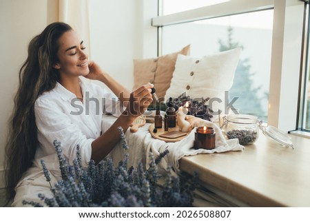 Young woman applying natural organic essential oil on hair and skin. Home spa and beauty rituals. Skin care. Stock fotó © 