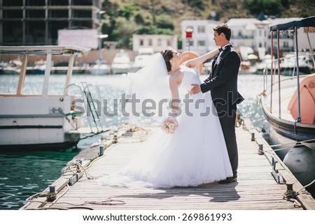 Just married couple posing in small cove with old boats
